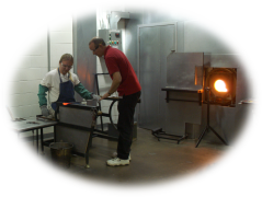 A picture of Piotr Mitros in a glassblowing shop doing something with a hot piece of glass